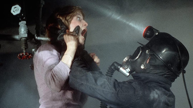 A man in a miner's outfit holds a woman up by the throat.