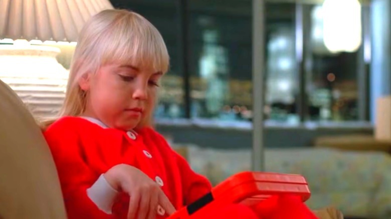 A young girl with blonde hair plays with a toy