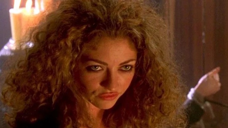 A woman with curly hair looks deviously off camera