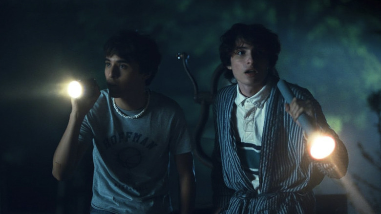 Bobby and Chris look around with flashlights in the woods at night in Hell of a Summer
