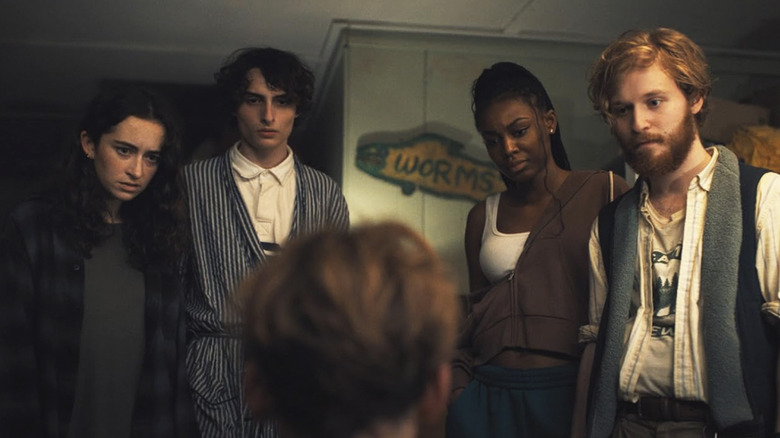 Claire, Chris, Shannon, and Jason look down at someone in a room at Camp Pineway in Hell of a Summer