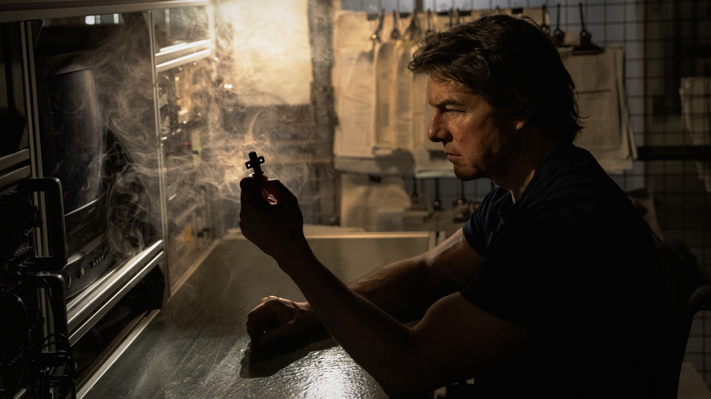 Tom Cruise as Ethan Hunt holding up a special key in a smoky room in Mission: Impossible - The Final Reckoning