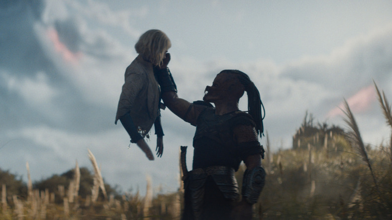 Dek mengangkat kepala dan dada Thia dengan latar langit asing di Predator: Badlands