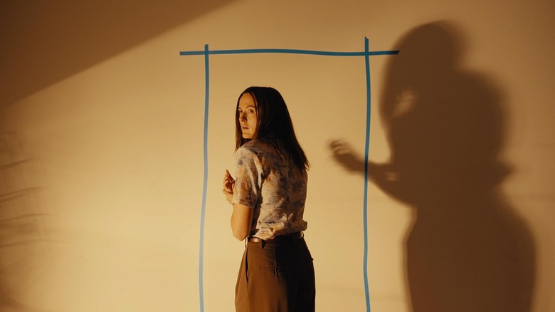 Renate Reinsve as Dr. Mary Kline standing next to a door sketched on a wall in Backrooms