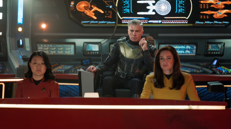 Rong Fu as Mitchell, Anson Mount as Captain Pike, and Rebecca Romijn as Una sitting at their stations in Star Trek: Strange New Worlds
