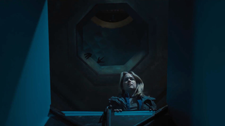 Elizabeth Lail as Vanessa looks inside a box as the silhouette of two claws appears behind her in Five Nights at Freddy's 2