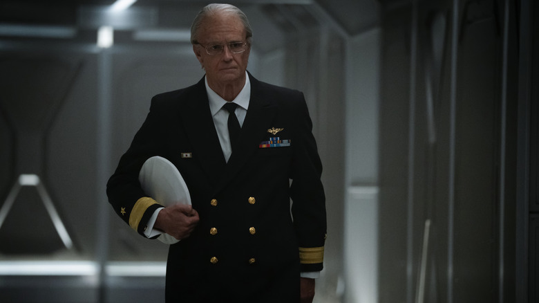 Joel Kinnaman as Ed Baldwin walking down a corridor in his admiral uniform and hat in hand in For All Mankind
