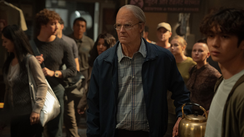 Joel Kinnaman as Ed Baldwin and Sean Kaufman as Alex Poletov Baldwin standing in a room filled with people in For All Mankind