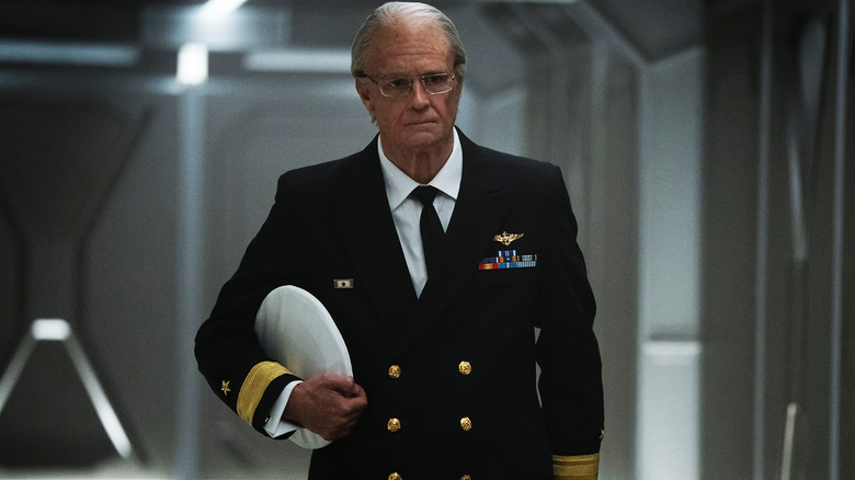 Joel Kinnaman's Edward Baldwin walks down a corridor holding his hat in For All Mankind