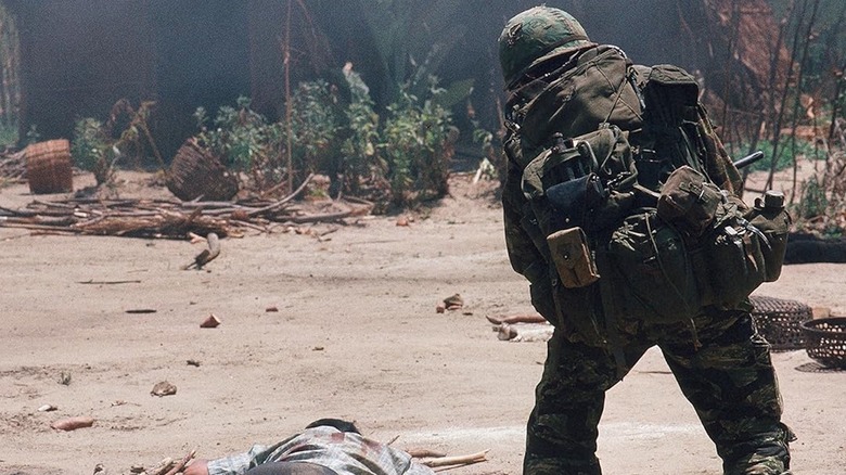 A soldier stands in front of a dead body in 84C MoPic