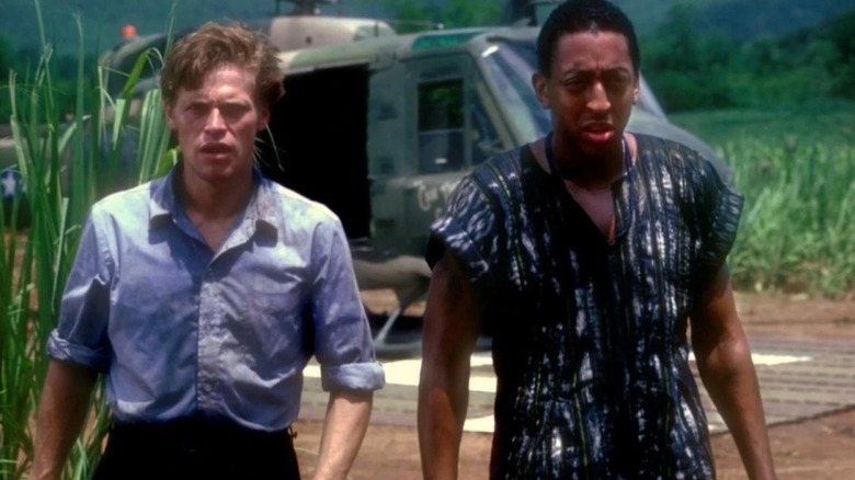 Willem Dafoe as Buck McGriff and Gregory Hines as Albaby Perkins stand in front of a helicopter in Off Limits