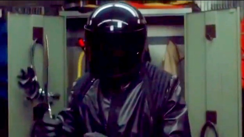 A killer in a motorcycle helmet is wielding a kukri in Night Schhol