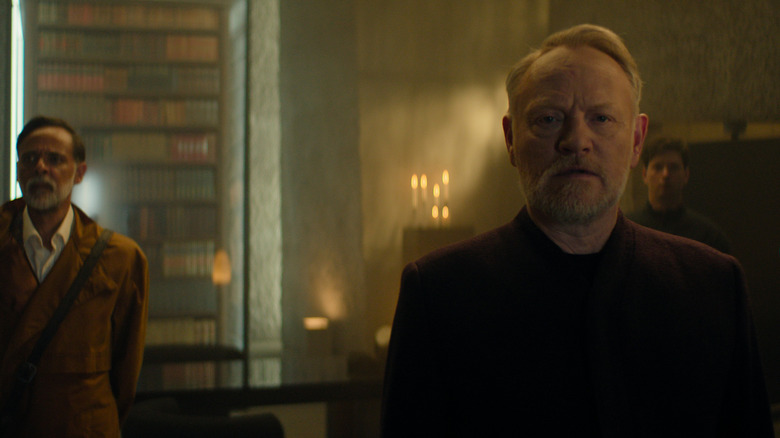 Alexander Siddig as Doctor Ebling Mis standing beside Jared Harris as Hari Seldon in a library in Foundation