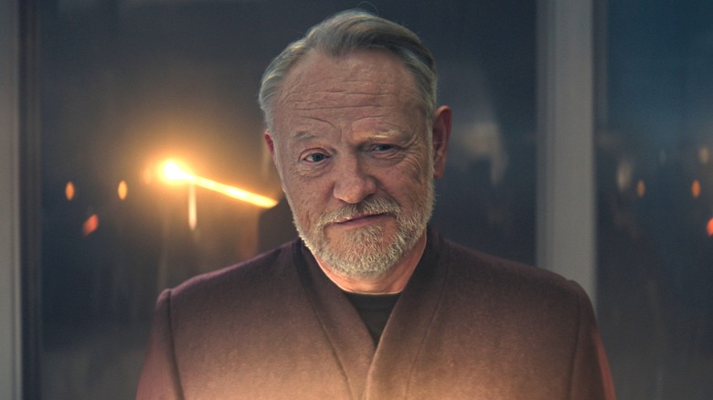 Hari Seldon with a concerned look while a laser beam fires behind him in Foundation