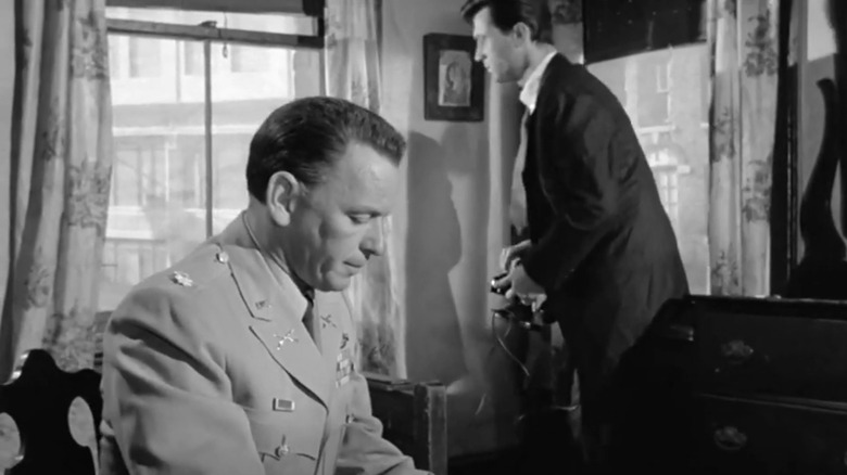 Frank Sinatra's Major Bennett Marco sits in a living room as Laurence Harvey's Raymond Shaw looks out the window in The Manchurian Candidate
