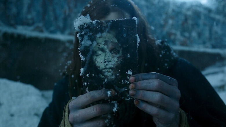 Frankenstein (2025) - the Creature holding up a photograph of himself to his face