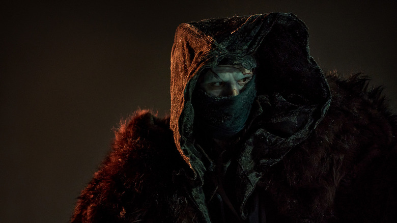 The Creature peers out from his hood in Frankenstein