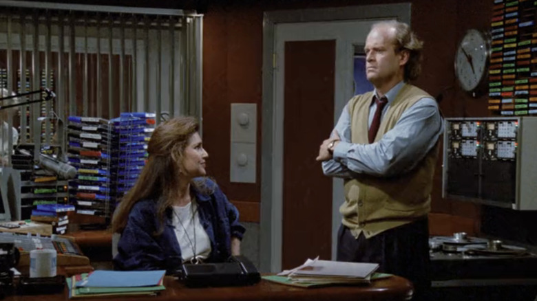 Kelsey Grammer's Frasier Crane and Perry Gilpin's Rose Doyle stand in the producer's booth in Frasier's radio studio