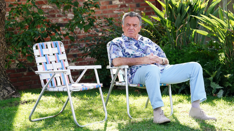 Ray Wise as Marvin Ellis grumpily sitting in a lawn chair in a yard Fresh Off the Boat