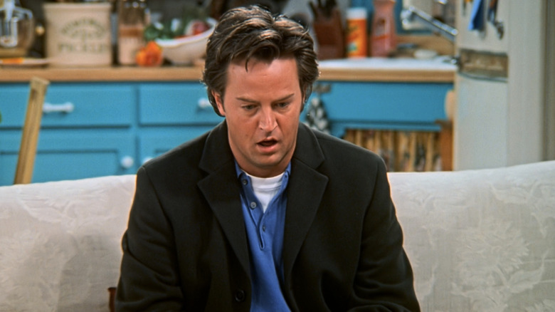 Matthew Perry's Chandler Bing looks shocked as he sits on a couch in Friends