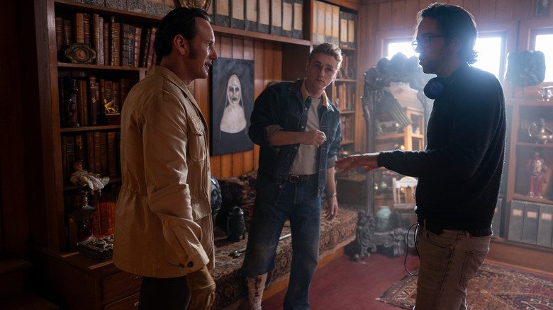 Director Michael Chaves standing next to Patrick Wilson as Ed Warren and Ben Hardy as Tony Spera on the set of The Conjuring: Last Rites