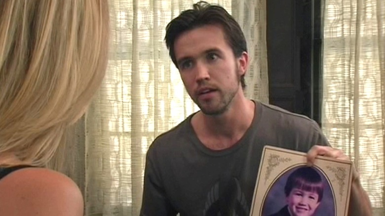 Rob Mac as Mac on It's Always Sunny in Philadelphia, holding up a picture of his younger self