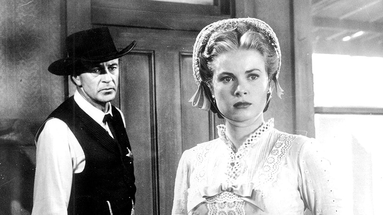 Gary Cooper as Marshal Will Kane, wearing a black cowboy hat, stares at the back of Grace Kelly as Amy Fowler Kane, who looks off to her left and is concerned