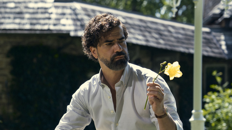 Hamish Linklater's Dean Cipher holding a flower on Gen V
