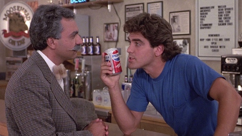 George Clooney as Matt Stevens holding up a can of Pepsi to a patron in Return of the Killer Tomatoes