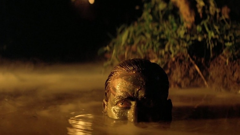 Captain Willard covered in mud and rising out of a bog in Apocalypse Now