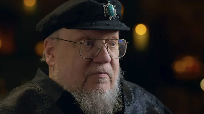 George R.R. Martin in a behind-the-scenes featurette for Game of Thrones, wearing a jaunty little cap with a turquoise turtle on it