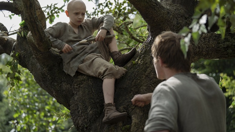 Dexter Sol Ansell as Egg seated in a tree and looking down on Peter Claffey as Ser Duncan the Tall in A Knight of the Seven Kingdoms