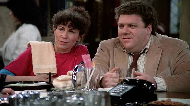 Rhea Perlman como Carla e George Wendt como norma sentada no bar em aplausos