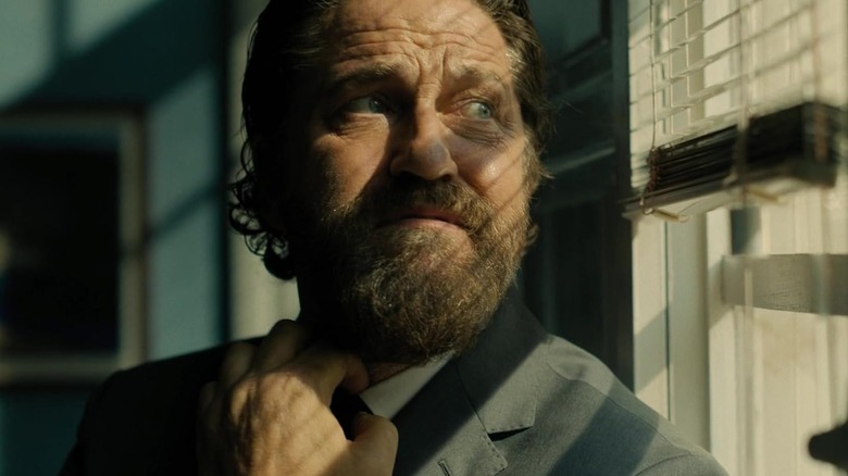 Gerard Butler as Nick straightening his tie in Den of Thieves 2: Pantera
