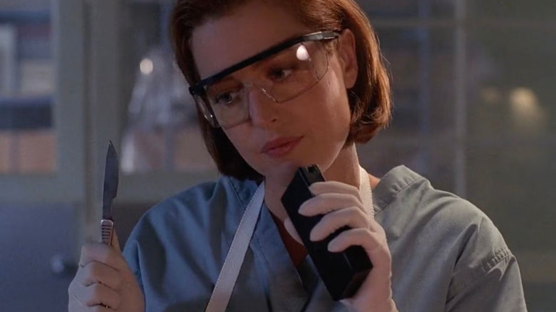 Dana Scully holding a scalpel, wearing hospital scribs, on The X-Files.