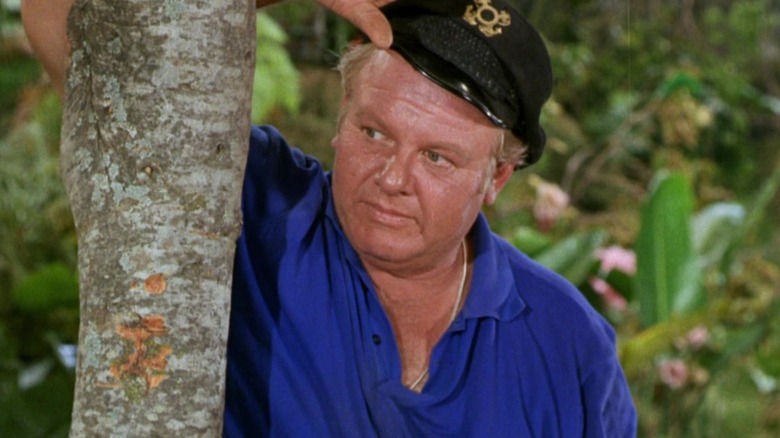 The Skipper leaning against a palm tree in Gilligan's Island