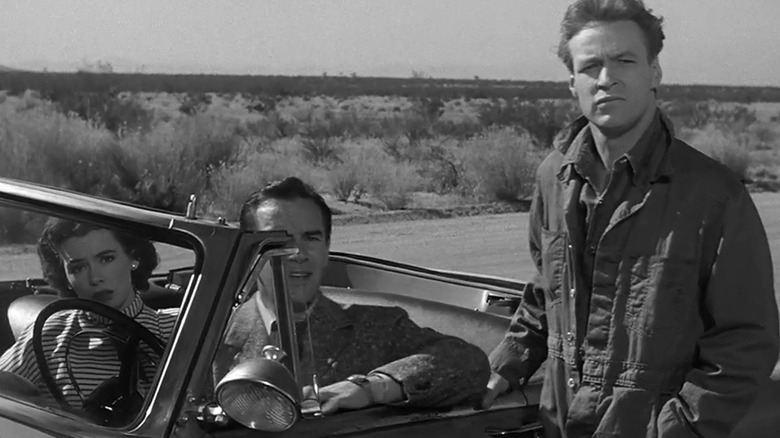 Barbara Rush's Ellen Fields and Richard Carlson's John Putnam sit in a car as Russell Johnson's George stands by the driver's side door in It Came from Outer Space