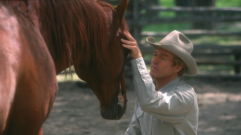 Robert Redford as Tom Booker whispers to a horse in The Horse Whisperer