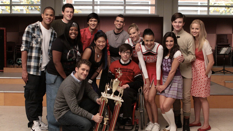 The cast of Glee pose for a picture in the music room