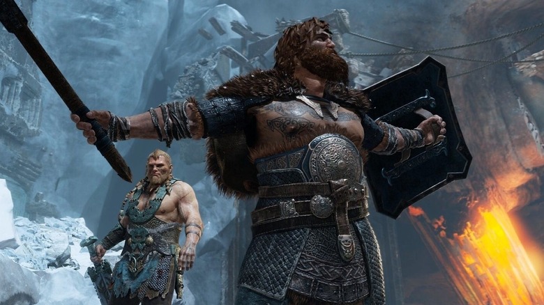 Troy Baker as the voice of Magni standing beside Nolan North as the voice of Modi in a frozen battlefield and holding weapons in God of War