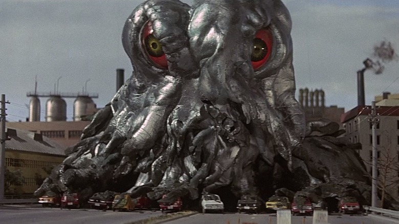 Hedorah eating up some cars outside a factory in Godzilla vs. Hedorah