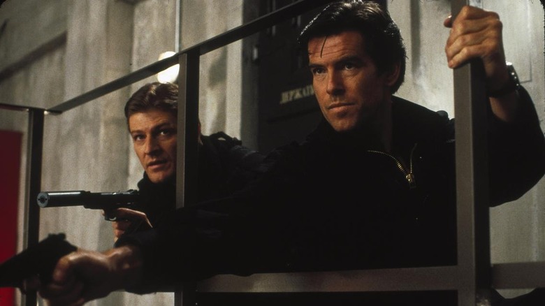 Sean Bean as Alec Trevelyan and Pierce Brosnan as James Bond crouched by one another with their guns out in GoldenEye