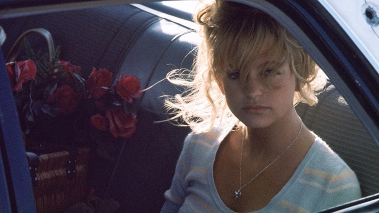 Goldie Hawn sits in the back seat of a car with a basket of roses as Lou Jean Poplin in The Sugarland Express