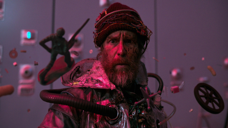 Sam Rockwell as the main character wearing a futuristic outfit and surrounded by floating objects in Good Luck, Have Fun, Don't Die