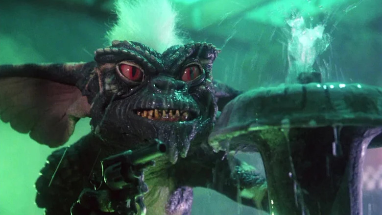 Stripe holding a gun with murderous intent and standing behind a fountain in Gremlins