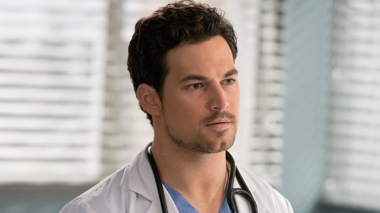 Andrew looking concerned wearing a stethoscope and white coat on Grey's Anatomy