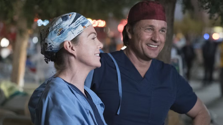 Meredith and Nathan laughing outside of the hospital in scrub caps on Grey's Anatomy