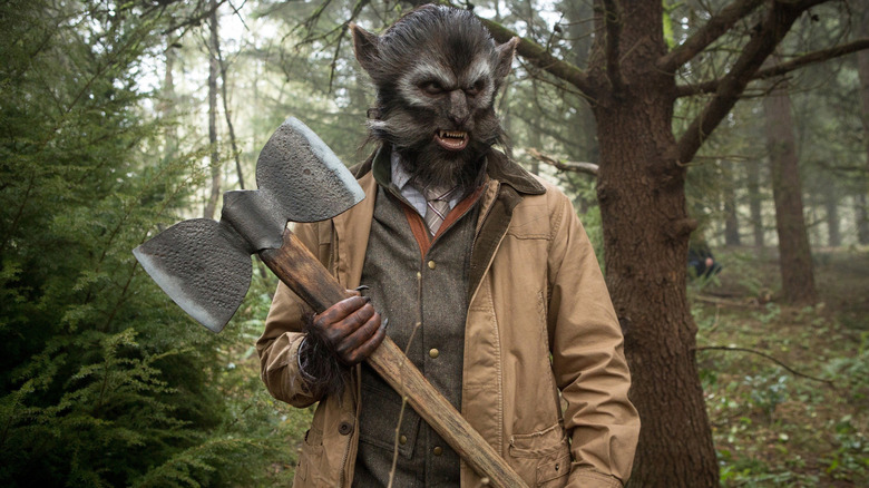 A blutbad holding an ax in the woods in Grimm