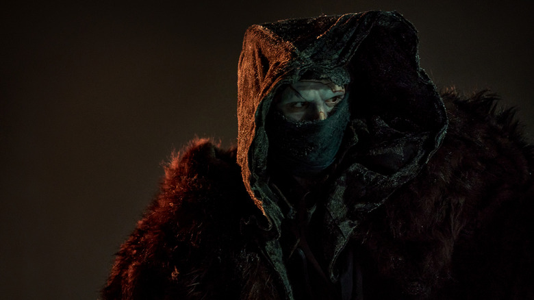 The Monster in a cloak with his face covered in the 2025 version of Frankenstein