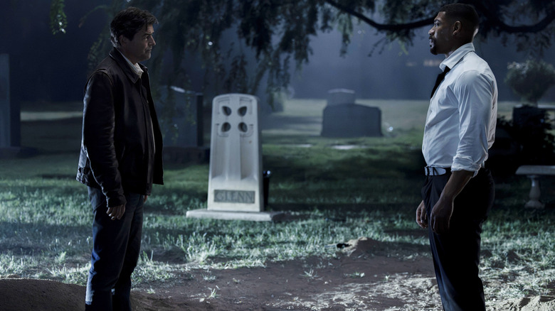 Kyle Chandler's Hal Jordan sits opposite Aaron Pierre's John Stewart stand opposite one another in a graveyard in Lanterns
